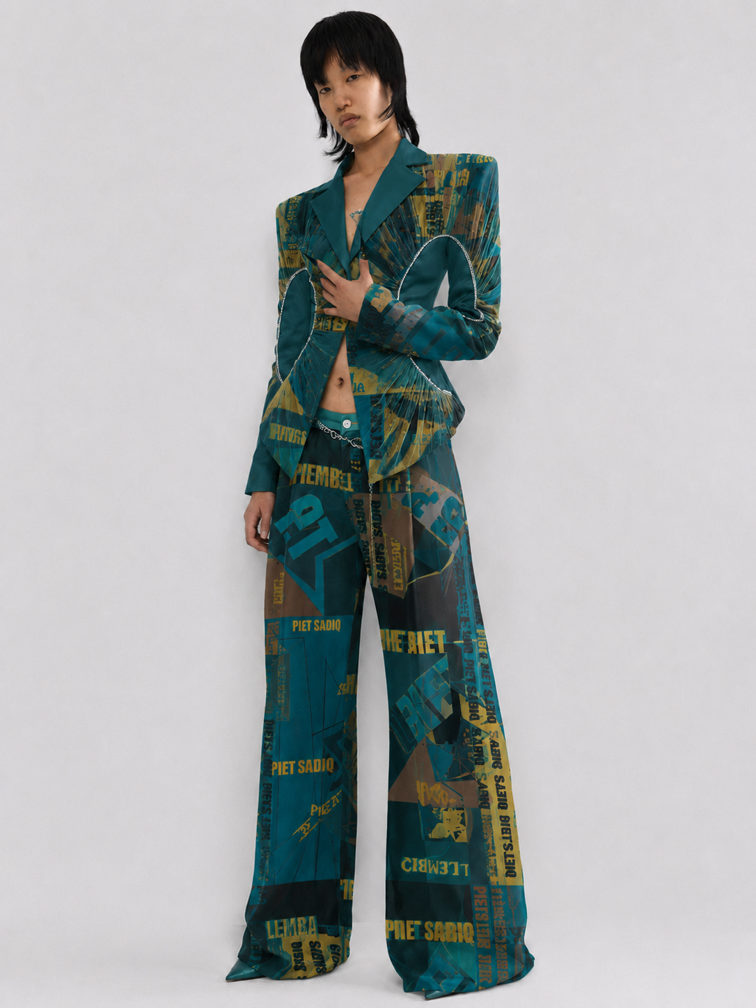Teal and mustard yellow graphic print suit, featuring a structured blazer and wide-leg trousers.