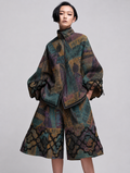Two-piece outfit consisting of a high-neck, oversized jacket and wide-leg shorts, both featuring a complex multicolor patchwork pattern with text, abstract shapes, and ornate cloud-like borders in teal, purple, gold, and black.